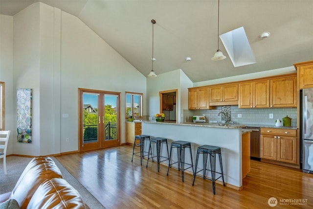 8705 Fenwick Loop SE, Olympia, WA 98513 - kitchen with high vaulted ceiling, a skylight, appliances with stainless steel finishes, a breakfast bar area, and light wood-style floors
