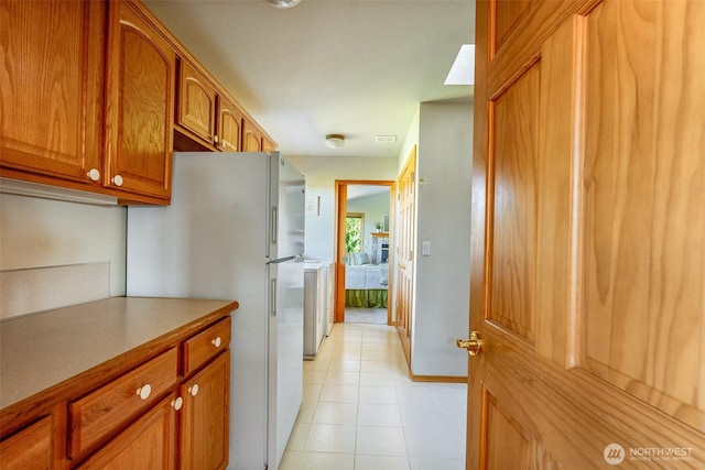 8705 Fenwick Loop SE, Olympia, WA 98513 - kitchen featuring freestanding refrigerator, brown cabinetry, light countertops, and light tile patterned floors
