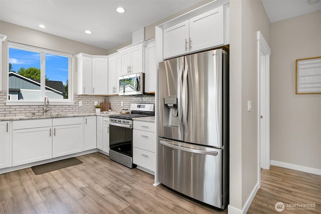 5690 Sunstone Pl Unit 101, Ferndale, WA 98248 - kitchen featuring stainless steel appliances, tasteful backsplash, white cabinetry, light wood-type flooring, and light stone countertops