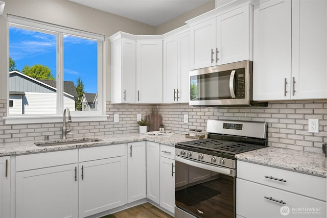 5690 Sunstone Pl Unit 101, Ferndale, WA 98248 - kitchen with appliances with stainless steel finishes, backsplash, white cabinets, and light stone counters
