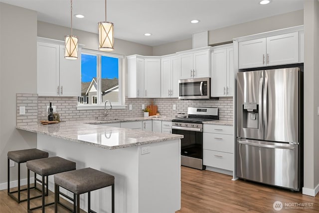 5690 Sunstone Pl Unit 101, Ferndale, WA 98248 - kitchen with stainless steel appliances, a peninsula, white cabinetry, tasteful backsplash, and recessed lighting