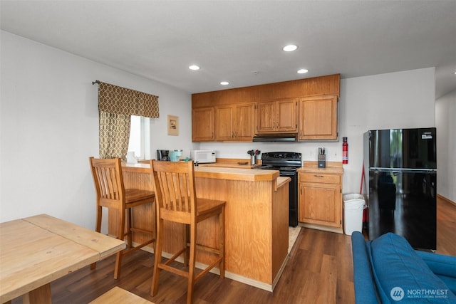 853 Ocean Shores Blvd NW Unit 4, Ocean Shores, WA 98569 - kitchen with black appliances, under cabinet range hood, dark wood-type flooring, light countertops, and recessed lighting