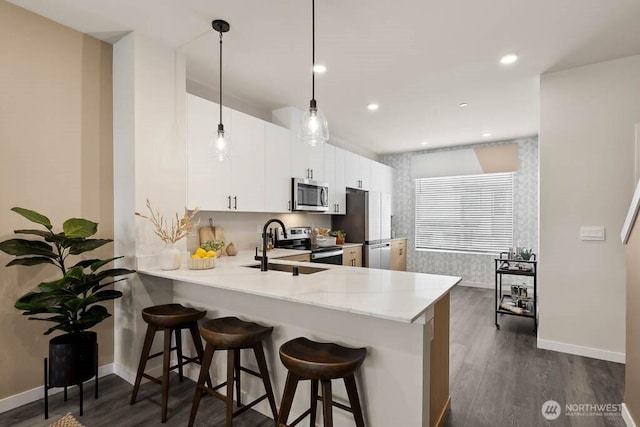 14707 87th Ave SE Unit V4, Snohomish, WA 98296 - kitchen with stainless steel appliances, a peninsula, dark wood-type flooring, a kitchen bar, and white cabinets