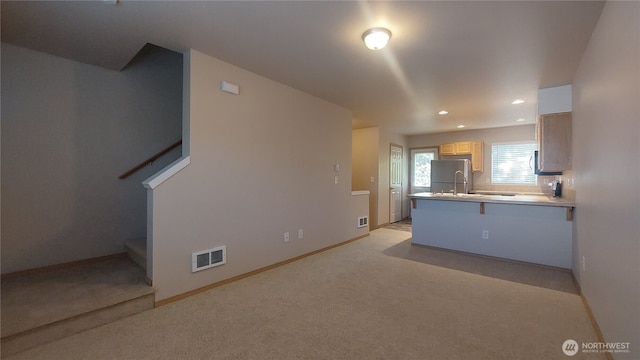 6907 Rainier Dr E Unit 1B, Everett, WA 98203 - kitchen with freestanding refrigerator, light carpet, a peninsula, recessed lighting, and a breakfast bar area