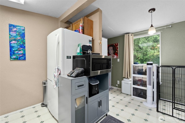 22517 133rd Street Ct E, Orting, WA 98360 - kitchen with light floors, stainless steel microwave, freestanding refrigerator, a textured ceiling, and hanging light fixtures