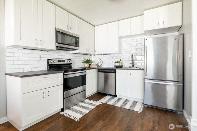 462 G St, Blaine, WA 98230 - kitchen featuring stainless steel appliances, dark countertops, dark wood-type flooring, and white cabinetry