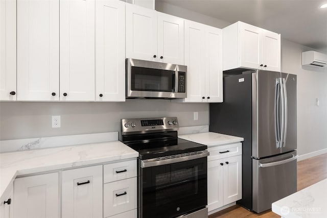 253 Kakela Rd, Winlock, WA 98596 - kitchen with stainless steel appliances, a wall unit AC, white cabinets, light wood-type flooring, and light stone countertops