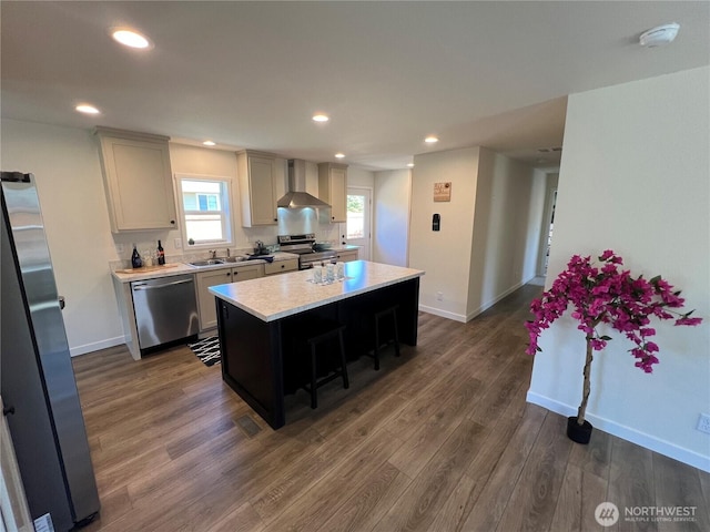 303 N Wynoochee Dr SW, Ocean Shores, WA 98569 - kitchen featuring appliances with stainless steel finishes, wall chimney exhaust hood, light countertops, a kitchen island, and dark wood-style floors