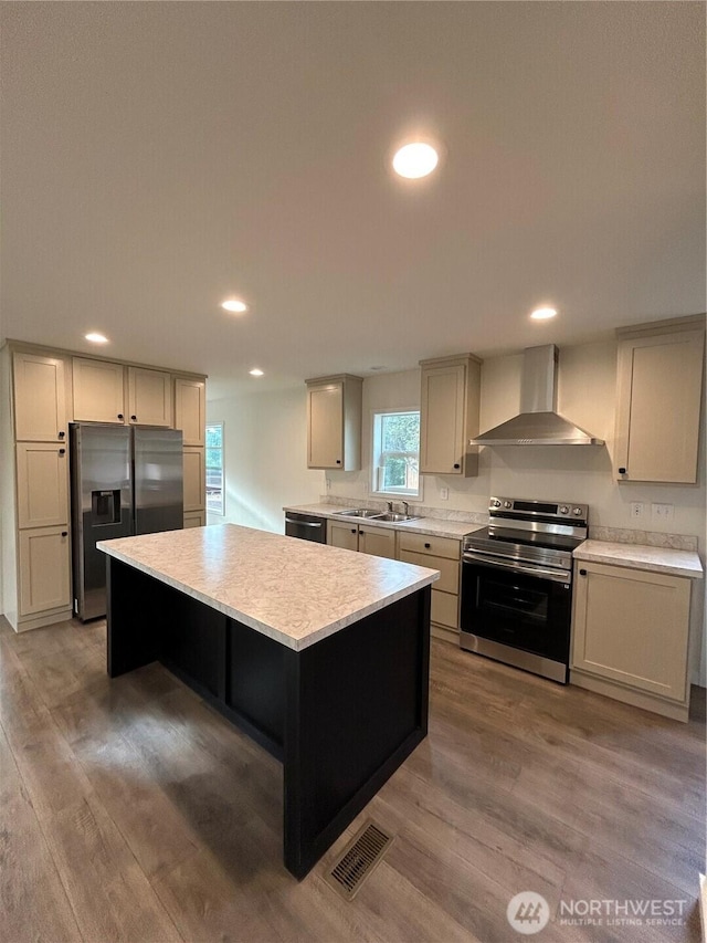 303 N Wynoochee Dr SW, Ocean Shores, WA 98569 - kitchen with appliances with stainless steel finishes, wall chimney exhaust hood, light countertops, a kitchen island, and wood finished floors