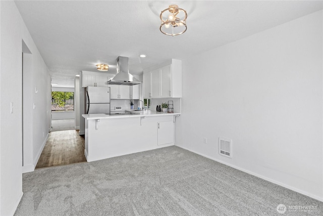 2235 E Wright Ave, Tacoma, WA 98404 - kitchen with exhaust hood, freestanding refrigerator, a peninsula, carpet floors, and white cabinets