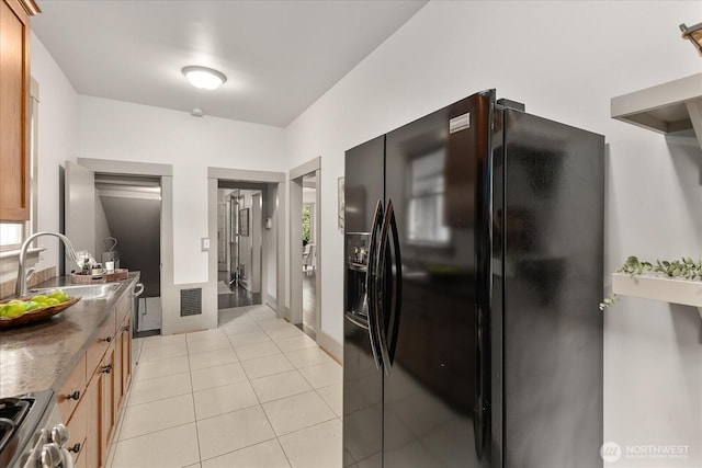 743 Broadway E, Seattle, WA 98102 - kitchen with black refrigerator with ice dispenser, stove, and light tile patterned floors