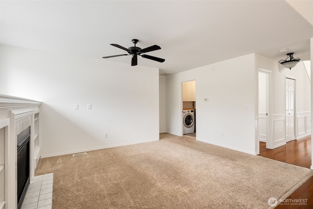 20122 102nd Ave SE, Kent, WA 98031 - unfurnished living room featuring washer / clothes dryer, a ceiling fan, a tiled fireplace, and light carpet