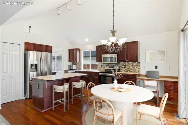 20122 102nd Ave SE, Kent, WA 98031 - kitchen featuring stainless steel appliances, vaulted ceiling, a center island, a chandelier, and decorative backsplash