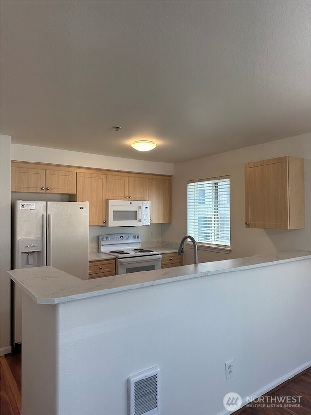 10511 Midvale Ave N Unit 202, Seattle, WA 98133 - kitchen featuring white appliances, light brown cabinetry, light countertops, and a peninsula
