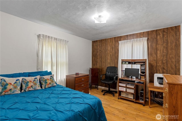 2434 NW Alan Ave, East Wenatchee, WA 98802 - bedroom featuring light wood finished floors, wooden walls, a textured ceiling, and a desk