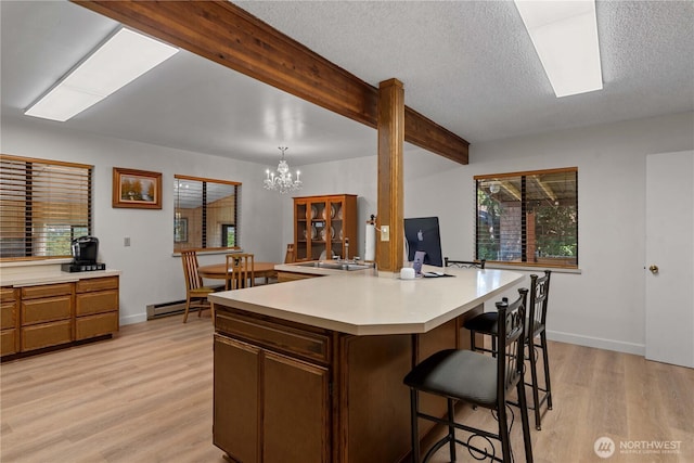 2434 NW Alan Ave, East Wenatchee, WA 98802 - kitchen with light countertops, light wood finished floors, a breakfast bar, beamed ceiling, and a chandelier