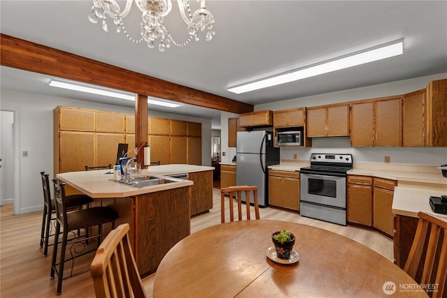 2434 NW Alan Ave, East Wenatchee, WA 98802 - kitchen featuring stainless steel appliances, light countertops, light wood-style floors, and a kitchen island with sink