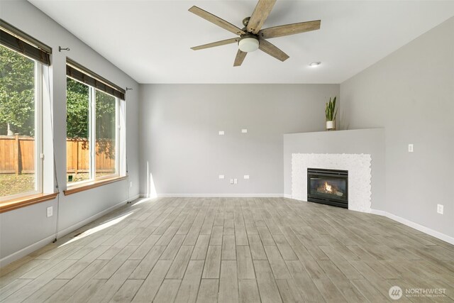 502 182nd St E, Spanaway, WA 98387 - unfurnished living room featuring light wood-style flooring, a ceiling fan, and a glass covered fireplace