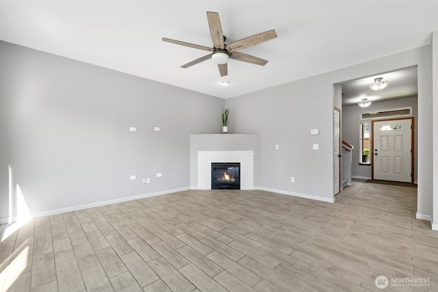 502 182nd St E, Spanaway, WA 98387 - unfurnished living room featuring light wood-type flooring, ceiling fan, a glass covered fireplace, and stairway