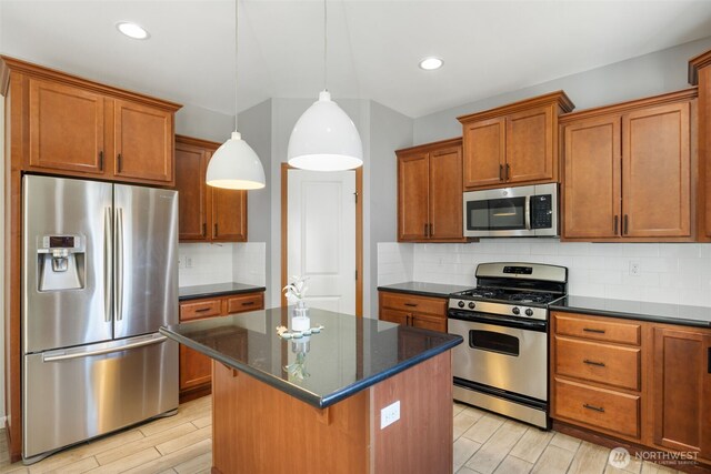502 182nd St E, Spanaway, WA 98387 - kitchen with appliances with stainless steel finishes, brown cabinets, a kitchen island, light wood-type flooring, and tasteful backsplash