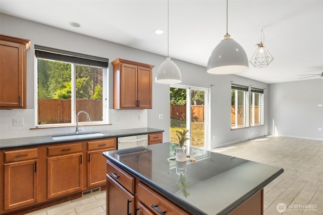 502 182nd St E, Spanaway, WA 98387 - kitchen featuring dark countertops, dishwasher, backsplash, open floor plan, and brown cabinetry