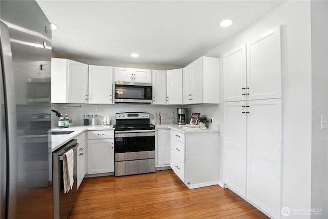 18844 SE 214th St, Renton, WA 98058 - kitchen with appliances with stainless steel finishes, light wood-style flooring, light countertops, white cabinetry, and recessed lighting