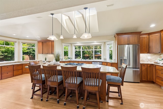 4101 Banbridge Loop SE, Olympia, WA 98501 - kitchen featuring appliances with stainless steel finishes, brown cabinets, light wood-style floors, a center island, and tasteful backsplash
