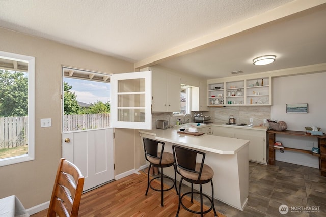 118 N Hemlock St, Soap Lake, WA 98851 - kitchen featuring open shelves, a peninsula, light countertops, white cabinetry, and a textured ceiling