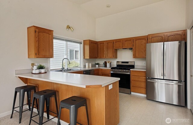 4896 Spinnaker Dr, Freeland, WA 98249 - kitchen featuring stainless steel appliances, high vaulted ceiling, a peninsula, light countertops, and brown cabinetry