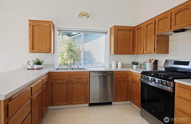 4896 Spinnaker Dr, Freeland, WA 98249 - kitchen with stainless steel appliances, light countertops, a peninsula, and brown cabinetry