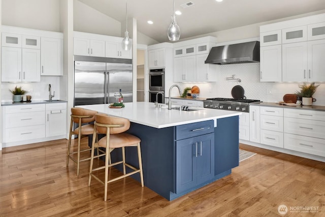 5754 W 26th Crst, Ferndale, WA 98248 - kitchen with wall chimney exhaust hood, appliances with stainless steel finishes, tasteful backsplash, white cabinets, and vaulted ceiling