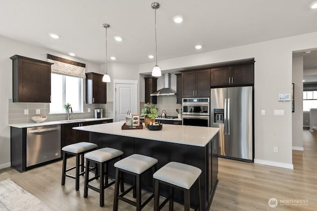 821 SE 12th Pl Unit 31, North Bend, WA 98045 - kitchen with appliances with stainless steel finishes, wall chimney range hood, dark brown cabinetry, light countertops, and light wood-style flooring