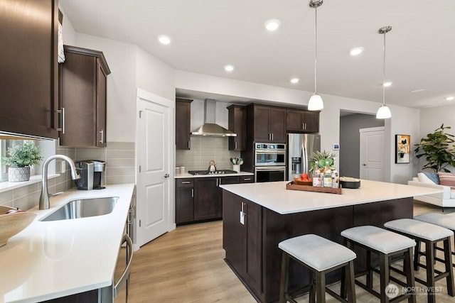 821 SE 12th Pl Unit 31, North Bend, WA 98045 - kitchen with wall chimney exhaust hood, appliances with stainless steel finishes, dark brown cabinets, a kitchen breakfast bar, and decorative backsplash