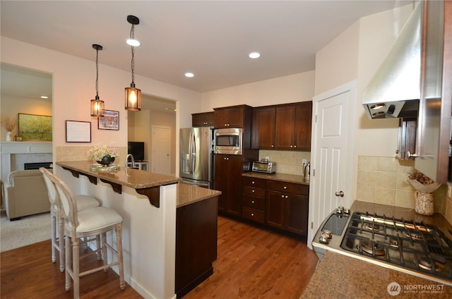 27719 NE 146th Way, Duvall, WA 98019 - kitchen featuring extractor fan, appliances with stainless steel finishes, a kitchen breakfast bar, dark wood-type flooring, and decorative backsplash