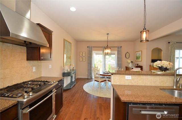 27719 NE 146th Way, Duvall, WA 98019 - kitchen featuring wall chimney range hood, appliances with stainless steel finishes, backsplash, light stone counters, and decorative light fixtures