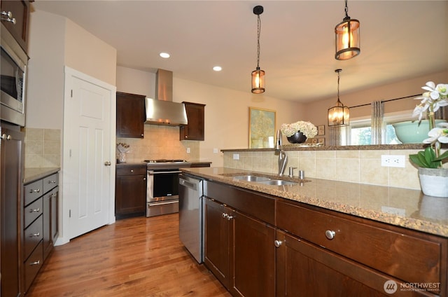 27719 NE 146th Way, Duvall, WA 98019 - kitchen featuring wall chimney range hood, appliances with stainless steel finishes, decorative backsplash, wood finished floors, and pendant lighting