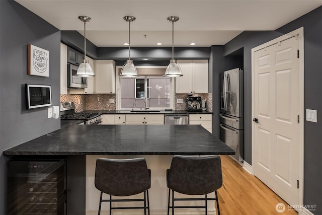 1416 6th Ave N, Seattle, WA 98109 - kitchen with wine cooler, stainless steel appliances, a peninsula, decorative backsplash, and white cabinetry