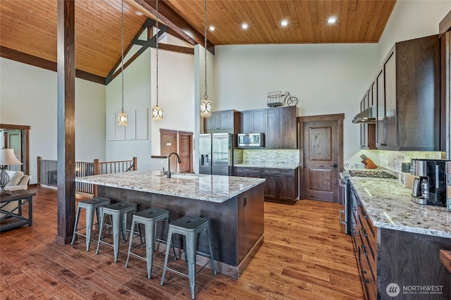 239 Foxridge Ln, Leavenworth, WA 98826 - kitchen with stainless steel appliances, high vaulted ceiling, a breakfast bar area, under cabinet range hood, and a wood ceiling with exposed beams