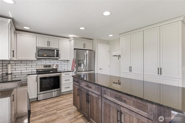 11389 Thompson Rd NE, Moses Lake, WA 98837 - kitchen featuring appliances with stainless steel finishes, recessed lighting, dark stone counters, backsplash, and light wood-style floors