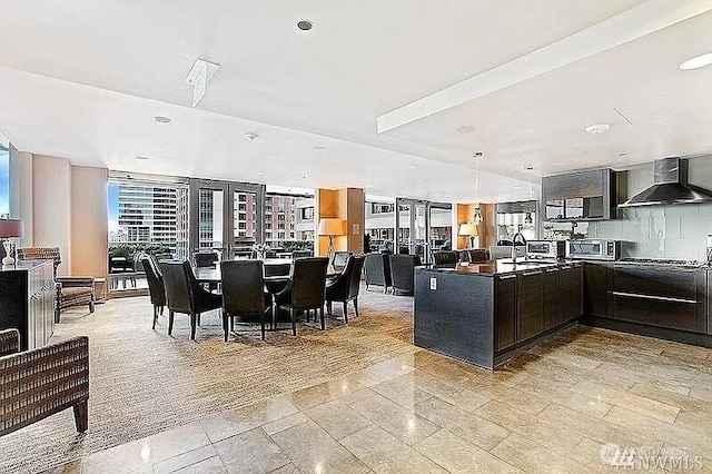 737 Olive Way Unit 3110, Seattle, WA 98101 - kitchen with wall chimney exhaust hood, stainless steel microwave, a peninsula, modern cabinets, and dark countertops