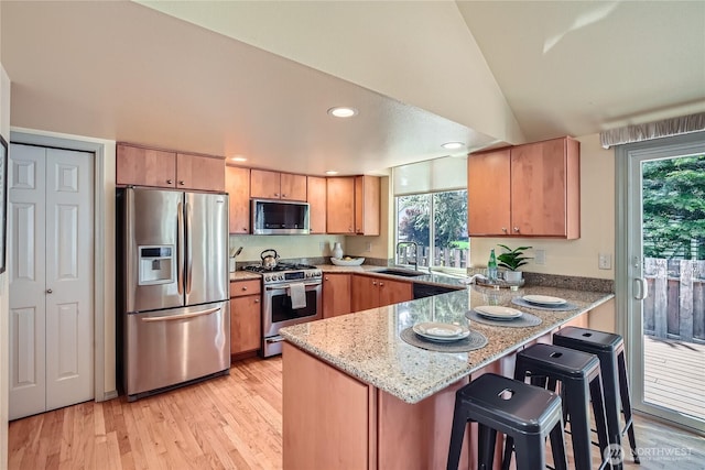 31451 48th Pl SW, Federal Way, WA 98023 - kitchen with appliances with stainless steel finishes, a peninsula, vaulted ceiling, light stone counters, and light wood-type flooring