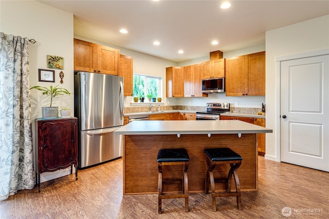 31 Nimbus Ln, Sequim, WA 98382 - kitchen featuring appliances with stainless steel finishes, a kitchen bar, light wood-style floors, a kitchen island, and light countertops