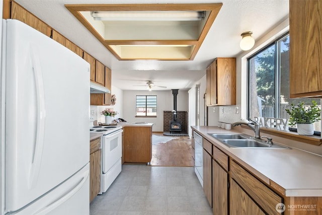 2528 S 363rd St, Federal Way, WA 98003 - kitchen featuring white appliances, under cabinet range hood, a wood stove, and brown cabinetry