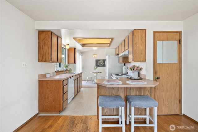 2528 S 363rd St, Federal Way, WA 98003 - kitchen with white appliances, brown cabinetry, under cabinet range hood, light countertops, and a peninsula