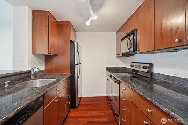 121 Vine St Unit 402, Seattle, WA 98121 - kitchen featuring appliances with stainless steel finishes, dark wood finished floors, track lighting, and dark stone counters