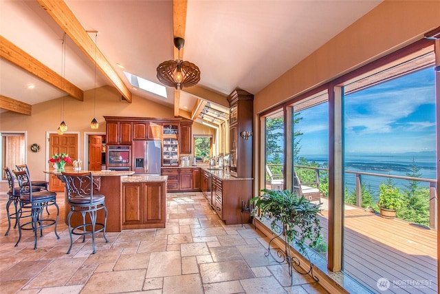 1669 Day Lake Rd, Orcas Island, WA 98245 - kitchen with stainless steel appliances, a water view, stone tile flooring, a skylight, and a kitchen breakfast bar