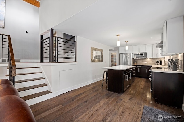 13 Westbrook Ct, Bellingham, WA 98229 - kitchen with stainless steel appliances, light countertops, dark wood-style flooring, a kitchen island, and a kitchen bar
