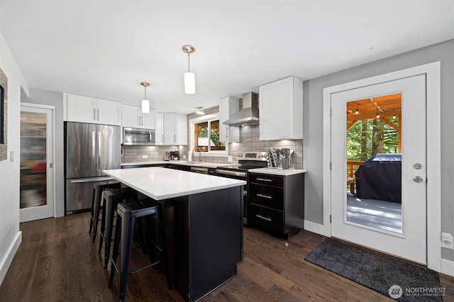 13 Westbrook Ct, Bellingham, WA 98229 - kitchen with appliances with stainless steel finishes, wall chimney range hood, light countertops, decorative backsplash, and a kitchen island