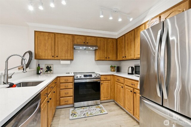 13216 NE 138th Pl, Kirkland, WA 98034 - kitchen featuring appliances with stainless steel finishes, under cabinet range hood, rail lighting, light countertops, and ornamental molding