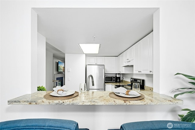 23335 Cedar Way Unit B204, Mountlake Terrace, WA 98043 - kitchen featuring appliances with stainless steel finishes, under cabinet range hood, a peninsula, and light stone countertops